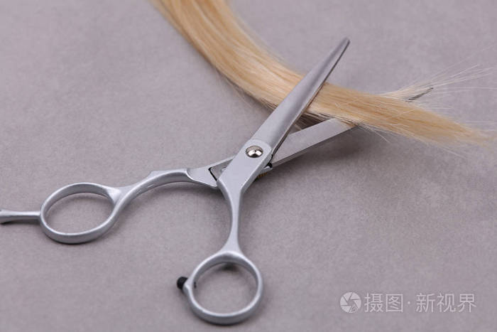 时尚专业理发剪刀梳子钢绞线的金发在灰色的背景上美发沙龙概念理发