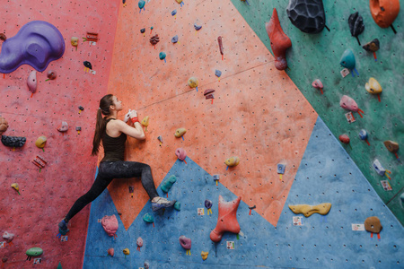 年轻的健身女人做专业抱石攀岩室内健身房
