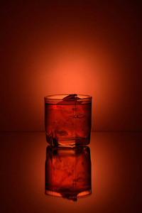 杯威士忌加冰上橙色背景与镜像