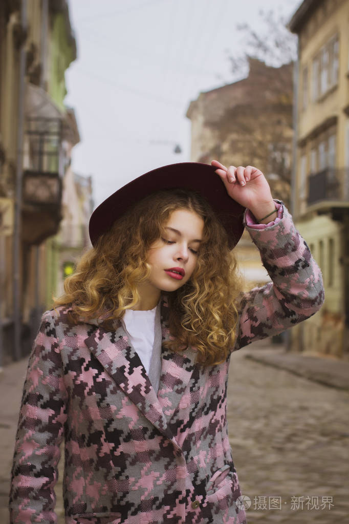 迷人的金发女人,红色的帽子在街上摆姿势