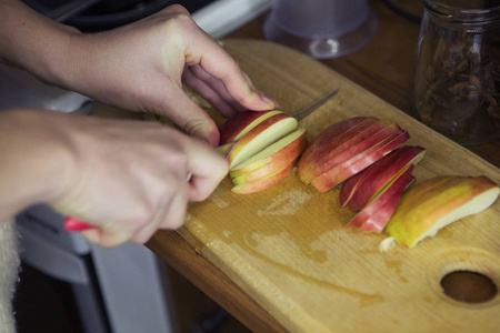 女人在她家中的厨房做饭。她切苹果为 c