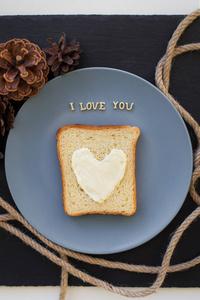 三明治早餐在奶酪上蓝色的盘子的心和黑色的背景，锥题字的形式，我爱你