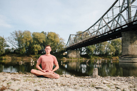 男人练瑜伽老桥附近的河岸上