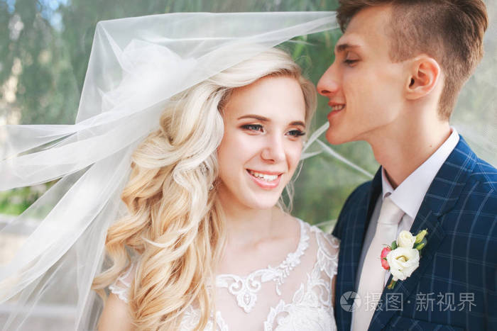 新娘和新郎上婚礼的一天,浪漫的结婚夫妇在美丽公园接吻照片-正版商用