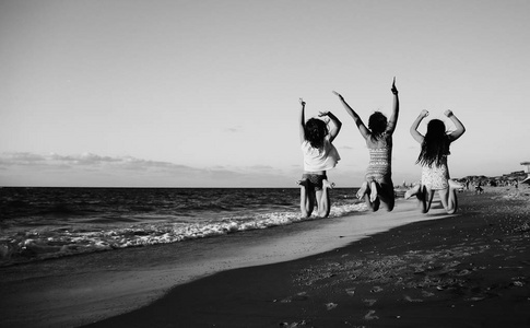 在沙滩上跳跃的三个女朋友