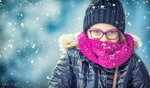 美冬季女孩吹雪在寒冷的冬季公园或户外。女孩和冬季寒冷的天气