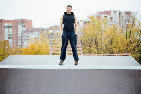 一个自信的健身家伙的画像。男子构成上溜冰斜坡，背景下城市