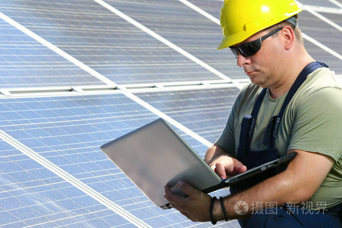 绿色能源，太阳能电池板和工人与笔记本电脑