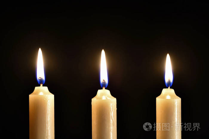 黑色背景上的三个燃烧蜡烛