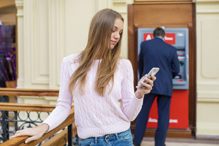 在购物中心 Atm 背景上的金发女人