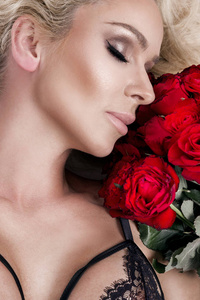 美丽的金发碧眼女人和令人惊异的看起来和长长的头发，完美的肌肤，她抱着红玫瑰情人节的花束