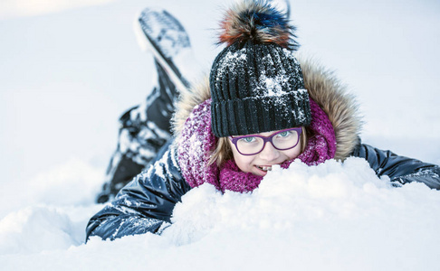 年轻的女孩正在玩雪。美冬天快乐女孩吹雪在寒冷的冬季公园或户外。女孩和冬季寒冷的天气
