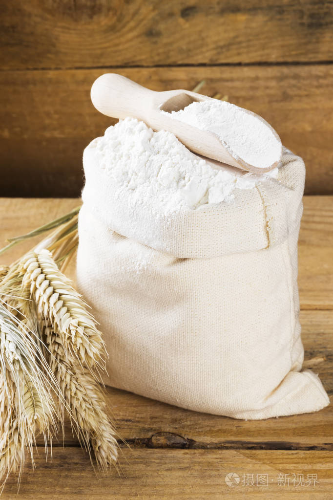 面粉袋和小麦中耳朵上木制的背景