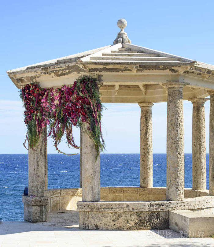 婚礼拱门上的地中海海岸。装饰精美的和浪漫的婚礼。石凉亭装饰为婚礼仪式