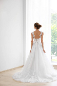 新娘穿着漂亮的婚纱站在窗边