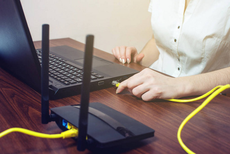 女人将网络电缆连接到笔记本电脑上的连接器