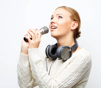 年轻女人对着麦克风戴着耳机在工作室里唱歌