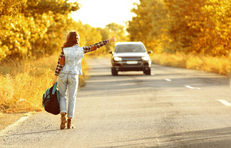 背包在公路上搭便车的年轻女子