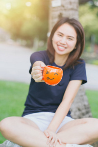亚洲女孩青少年工作妇女成人手柄微笑的咖啡杯的绿色公园