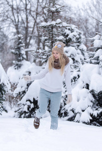 有吸引力的微笑年轻金发女孩走在冬季森林。冬季室外的漂亮女人。冬天穿的衣服。针织的毛衣 围巾 帽子和手套