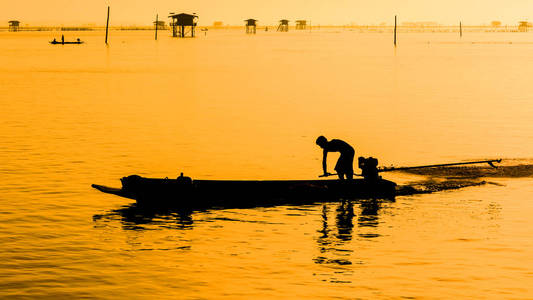男人在日落时分划小船的轮廓。Bangtabun Phetchabu