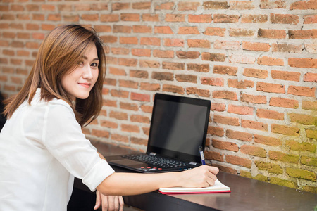 微笑工作妇女思想做工作，业务工作的作家认为，写在笔记本或计算机笔记本电脑