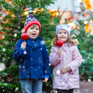 两个小孩子吃糖苹果上圣诞市场