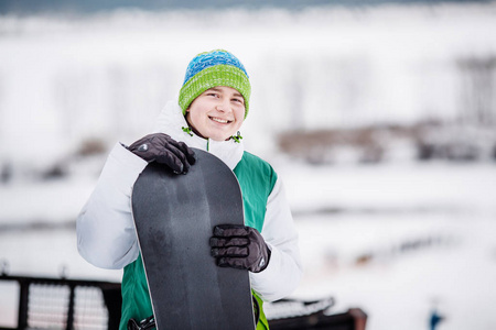 年轻人拿着滑雪板站在雪地上