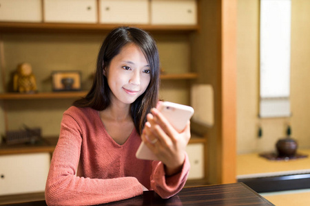 在餐厅中使用移动电话的女人