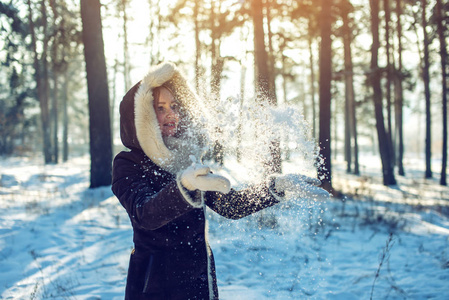 有魅力的女人在日落时吐到空中的雪