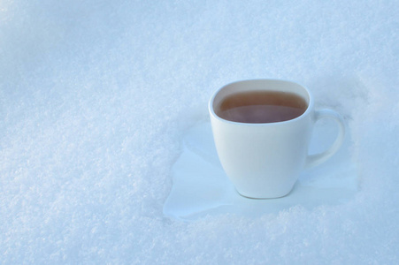 在雪背景上的白色杯子喝些热饮料