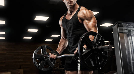 英俊的男人用大块的肌肉，在健身房中的相机摆姿势