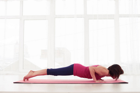 健身女人在瑜伽垫上做海豚木板构成