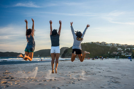 三名妇女在海滩上跳跃