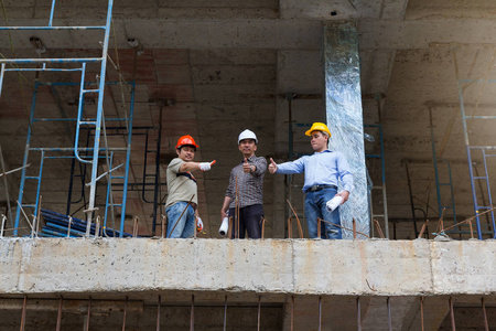 工程师和建筑师在建筑地盘工作与蓝图