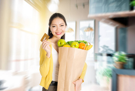 亚洲女人在市场举行食品杂货袋和信用卡
