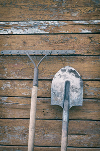 肮脏的铲子和耙背景彩绘木墙上，复古色调