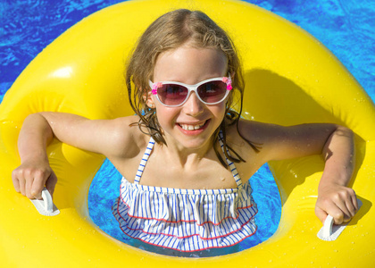 小女孩用充气橡胶圈在游泳池里的肖像