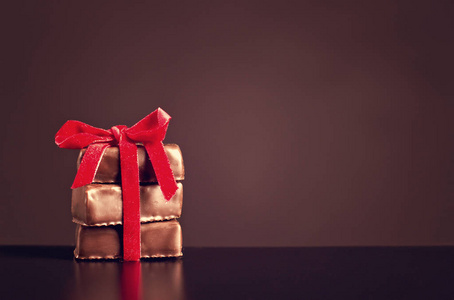 巧克力糖果与情人节的黑暗背景上的红丝带