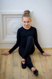 年轻的芭蕾舞演员坐在墙边