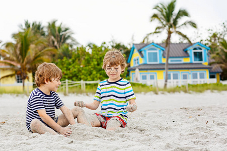 两个孩子男孩建设热带海滩上的沙堡