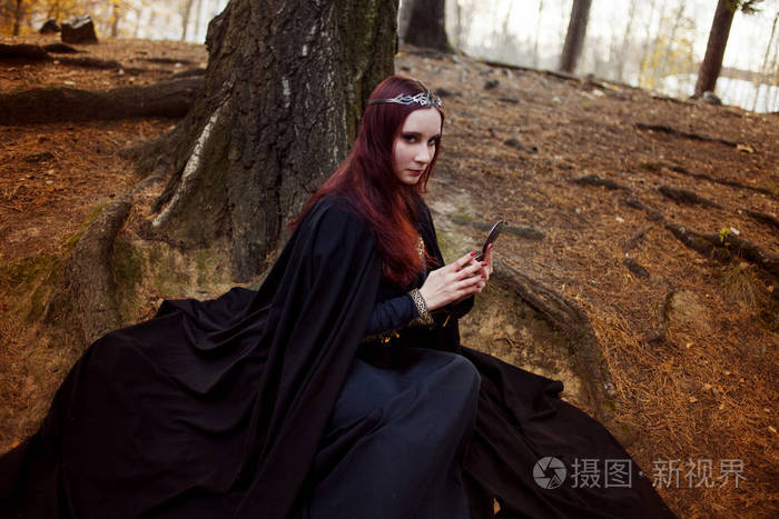 年轻美丽和神秘的女人的森林精灵或女巫,看镜子里的图像