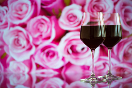 两杯红酒与火花和玫瑰散景背景。非常浅的景深。选择性的焦点，副本空间