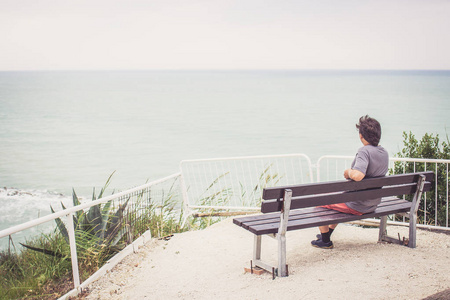 年轻人坐在长椅上俯瞰大海