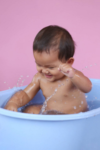 亚洲婴儿沐浴在蓝色泳池与快乐