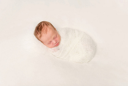 裹着白色服装婴儿睡在毯子上的滑稽