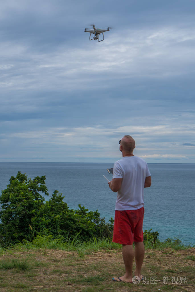 男人用无人机相机拍摄照片,美丽的大海