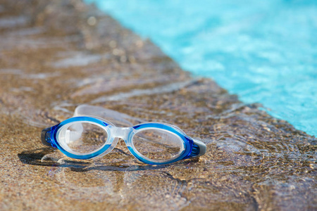 蓝色游泳护目镜隔离在游泳池边与副本 s