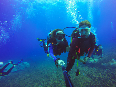 水下夫妇水肺潜水拍照拍摄的自拍照棍子。深蓝色的大海。广角拍摄