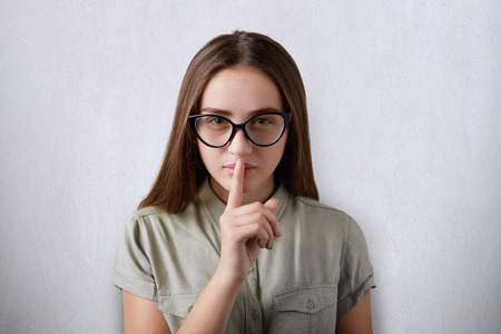 儿童姿态一张照片的黑直发与自信的脸,戴着眼镜在灰色的背景孩子把